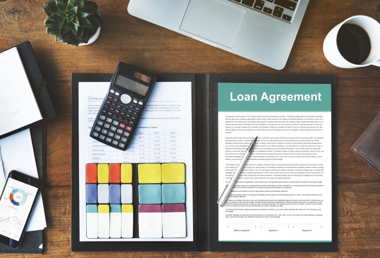"Smart Choices When Refinancing Your Home Loan: Essential tools for financial planning - Calculator, loan agreement, pen, sticky notes, cup of coffee, and mobile phone, all at Tradewise Solutions."